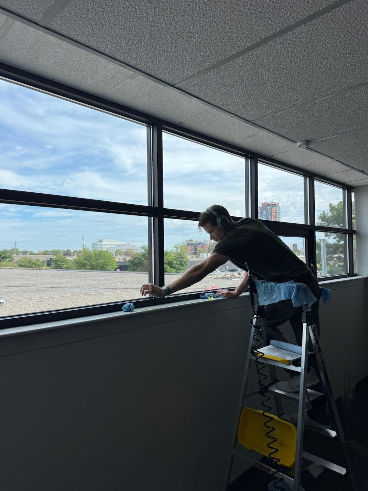 Winsolux installer finishing a run of office windows from a ladder