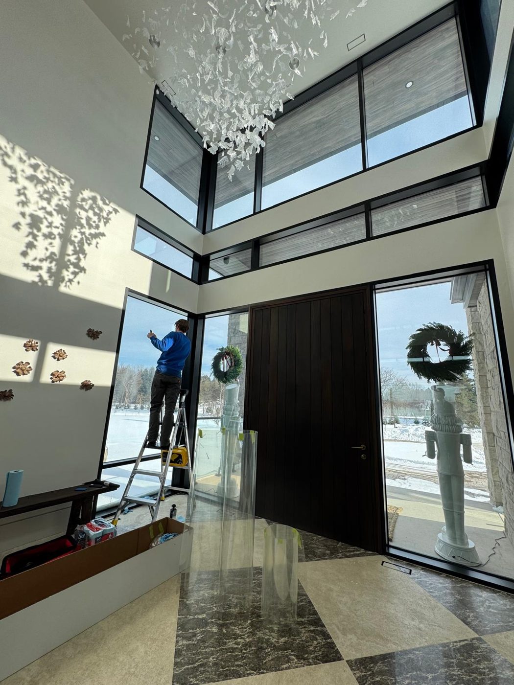 Installer applying film to two-storey foyer glass